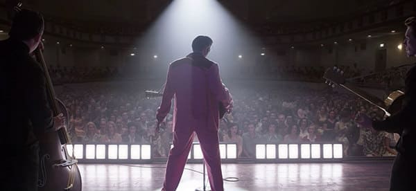 Picture of that back of a man on stage in front of an audience for the new film Elvis